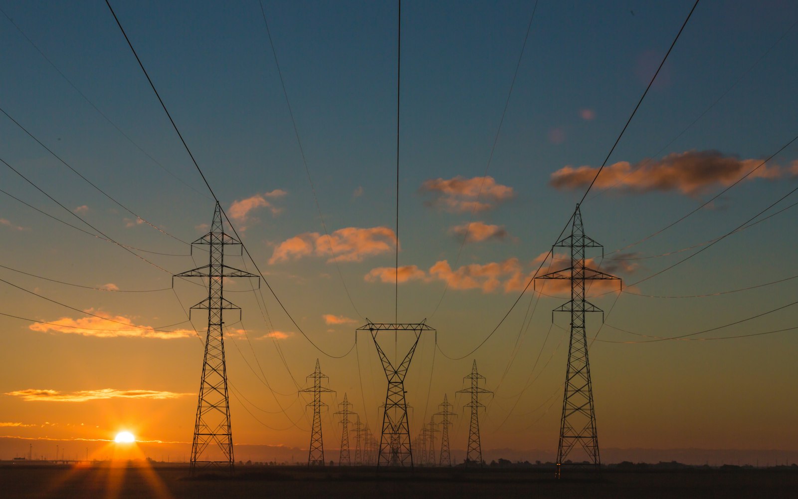 Transmission line corridor receding to the horizon at sunrise
